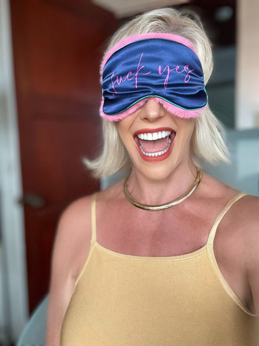 A woman wearing a blue and pink BDSM eye mask, showcasing a blend of elegance and allure in her expression