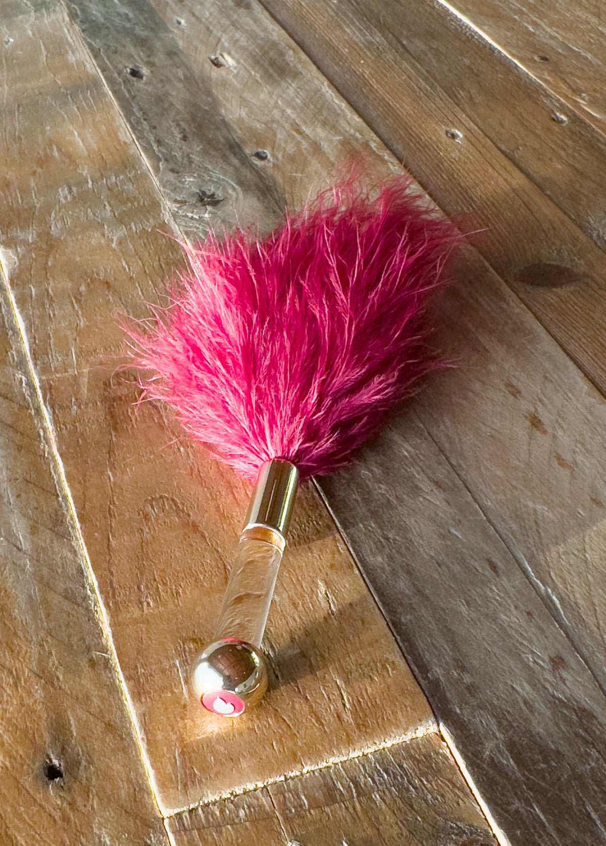 Fluff Puff downy feather tickler for sensation play on wood surface