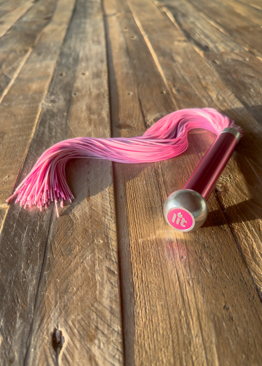 Pink Flogger on a wooden floor in sunlight